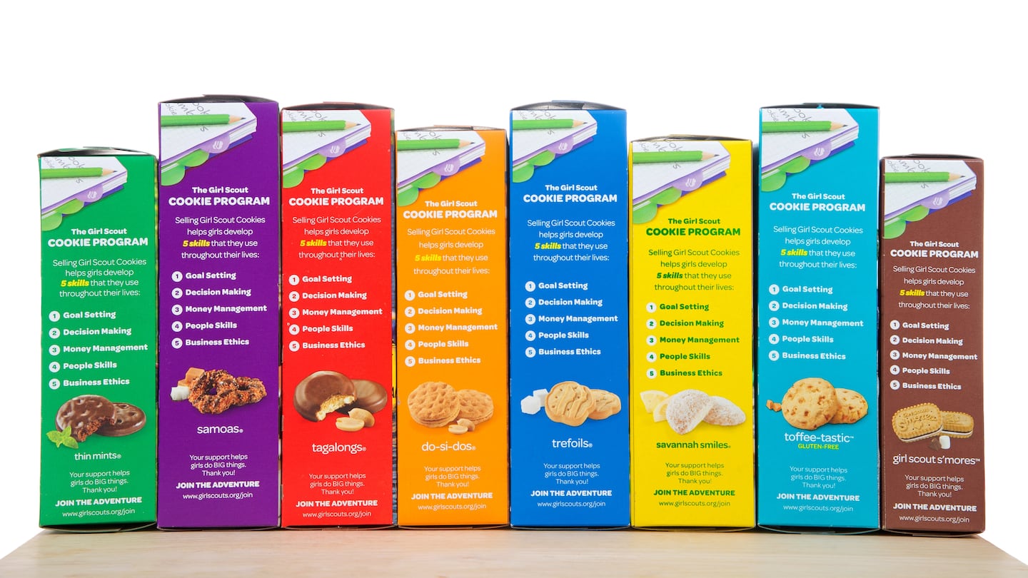 Brownie Baker brand Girl Scout cookies, all eight flavors on a wood table isolated on white background. Cookie sales raise funds for troop lead events and activities.