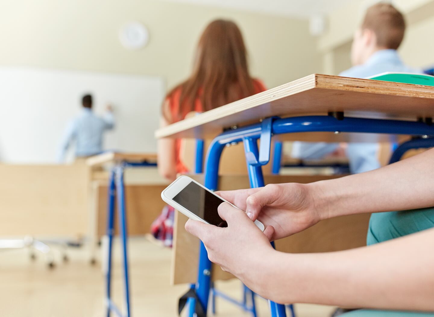 education, high school, learning, technology and people concept - student boy hands with smartphone texting on lesson