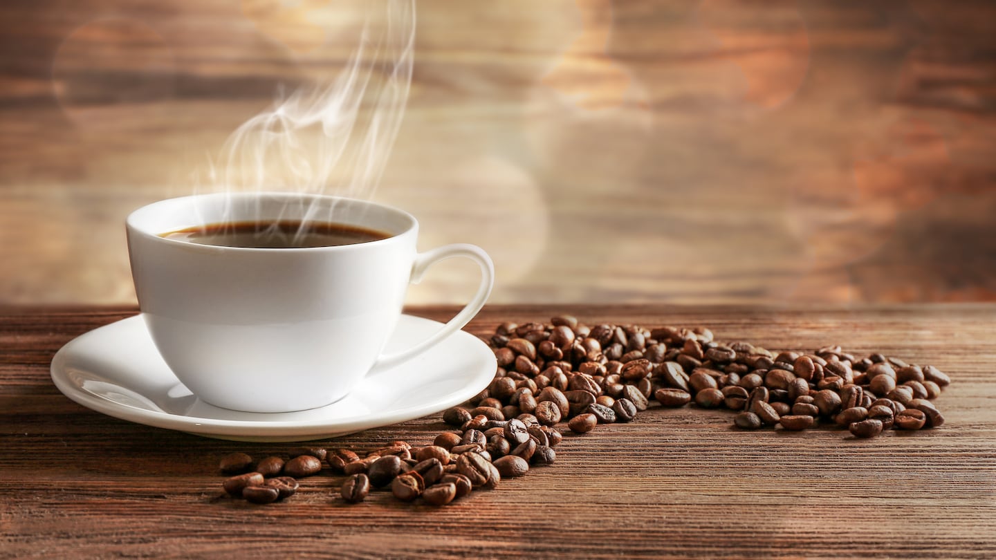 Cup of coffee with grains on wooden background